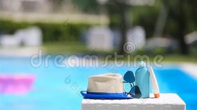 游泳池附近有防晒霜、帽子、太阳镜